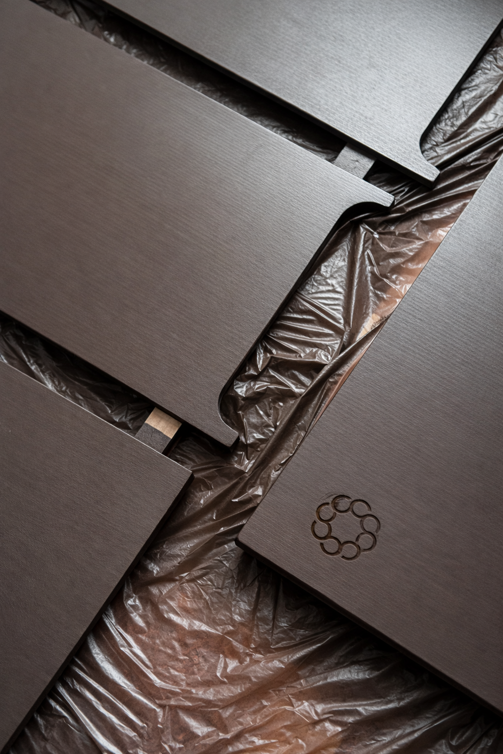 Close-up of metallic gray rectangular panels with a circular logo cutout, laid on protective plastic.