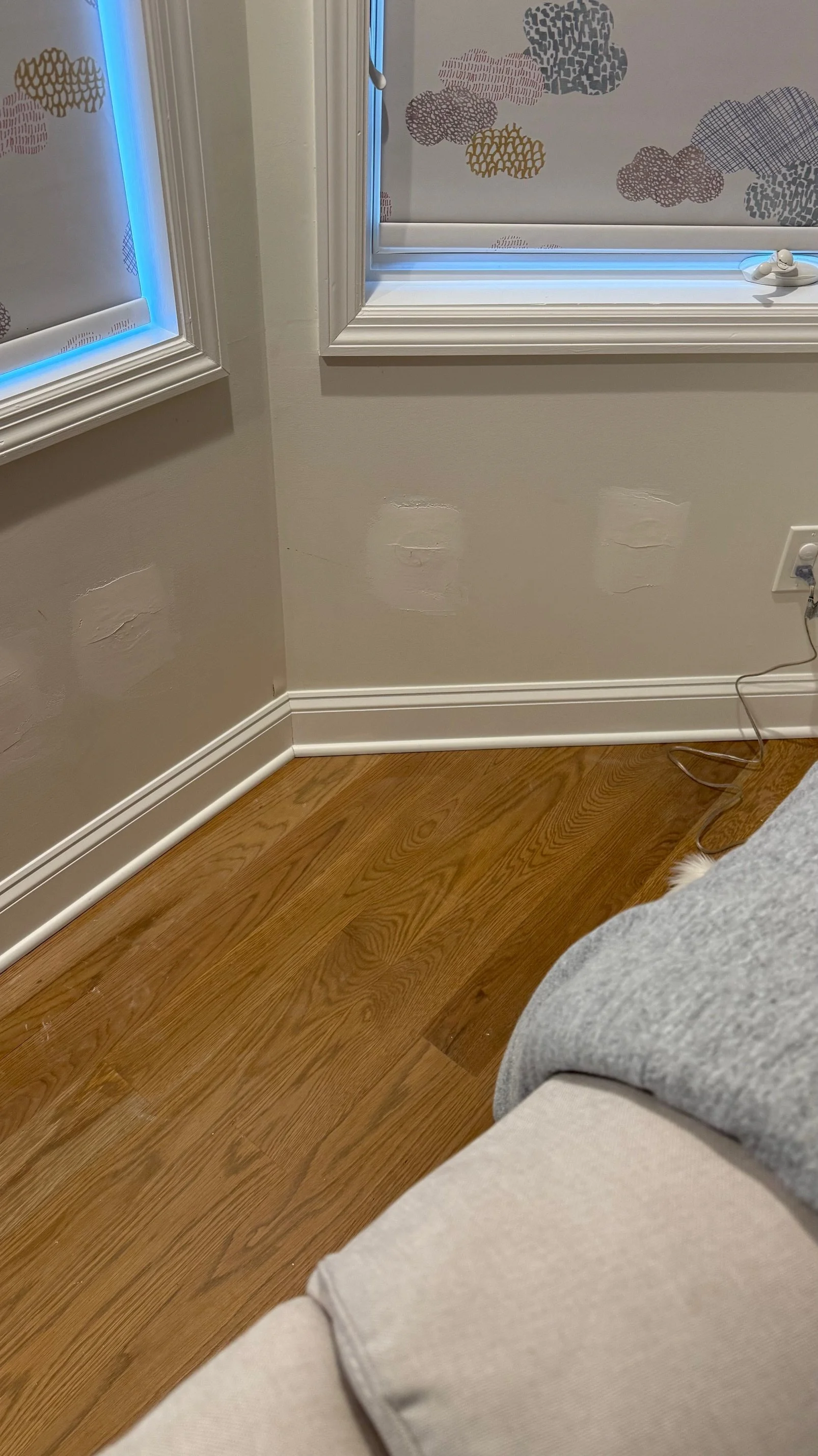Living room corner with beige wall that has patches for repainting, patched holes in the wall . minimal invasive insulation. no tear down wall. fill insulation. drain and fill insulation. retrofit insulation