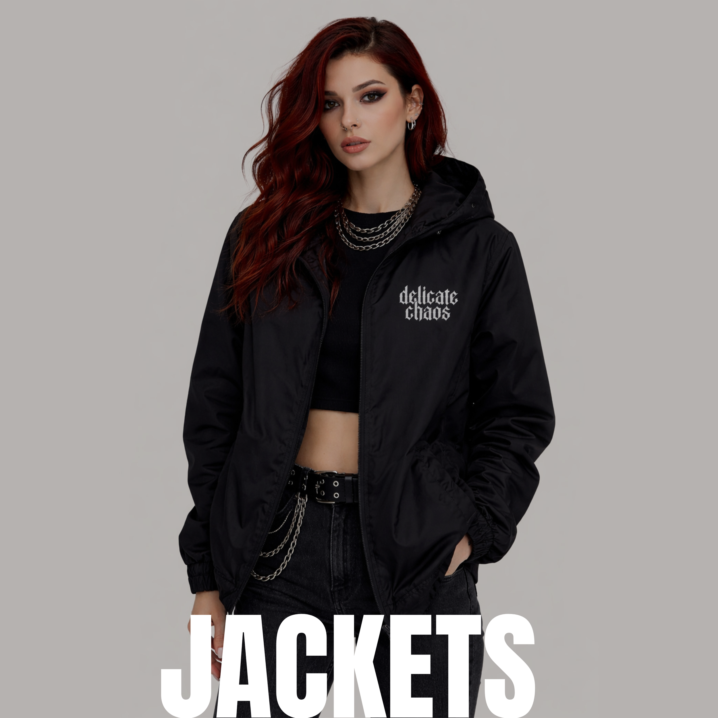 A young woman with long red wavy hair wearing black clothing and accessories, modeling a black jacket with the phrase 'delicate chaos' embroidered on it, standing against a light gray background. The word 'JACKETS' is overlaid at the bottom of the image.