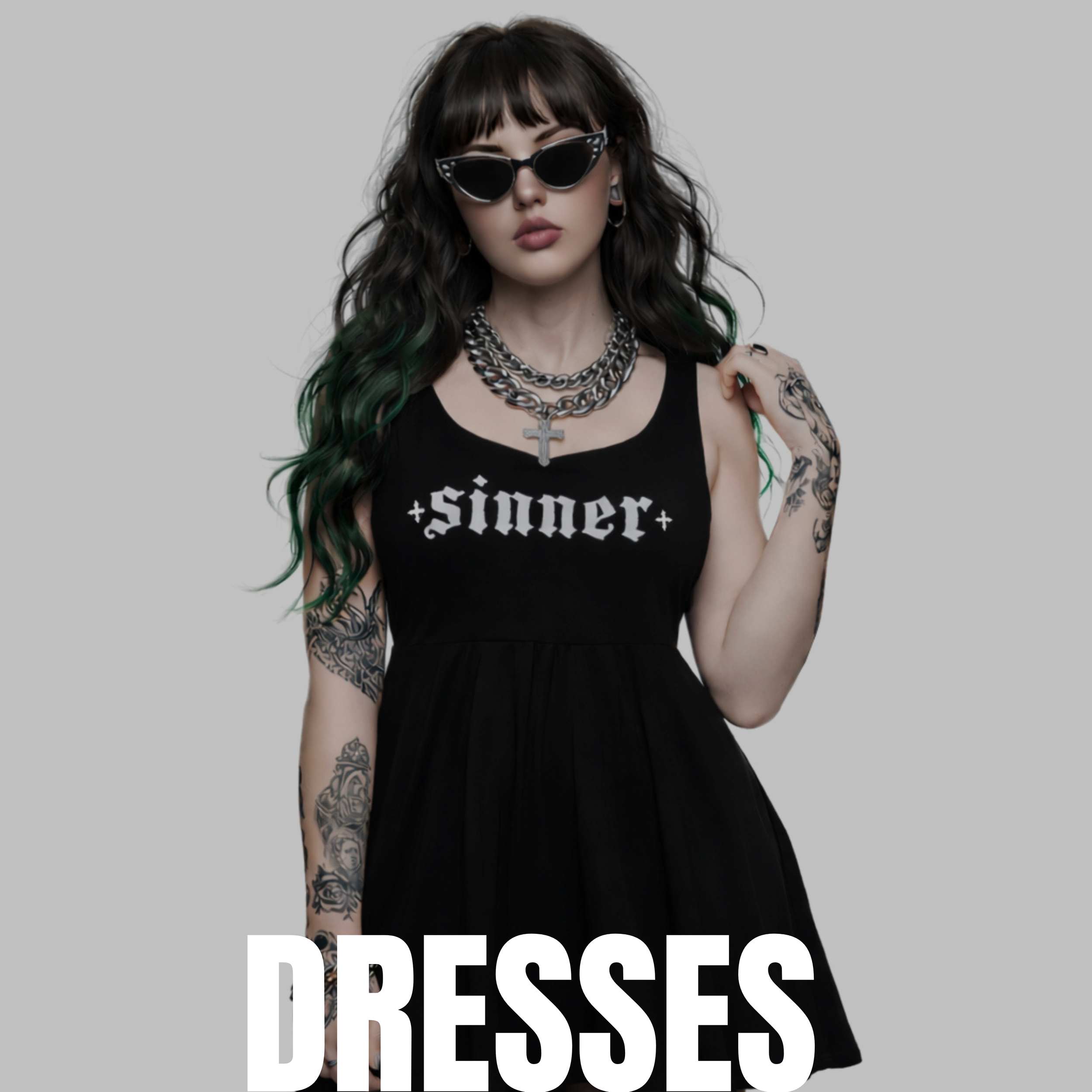 A woman wearing sunglasses, a black sleeveless dress with 'sinner' written on it, layered necklaces, and tattooed arms, standing against a plain gray background with the word 'DRESSES' at the bottom.