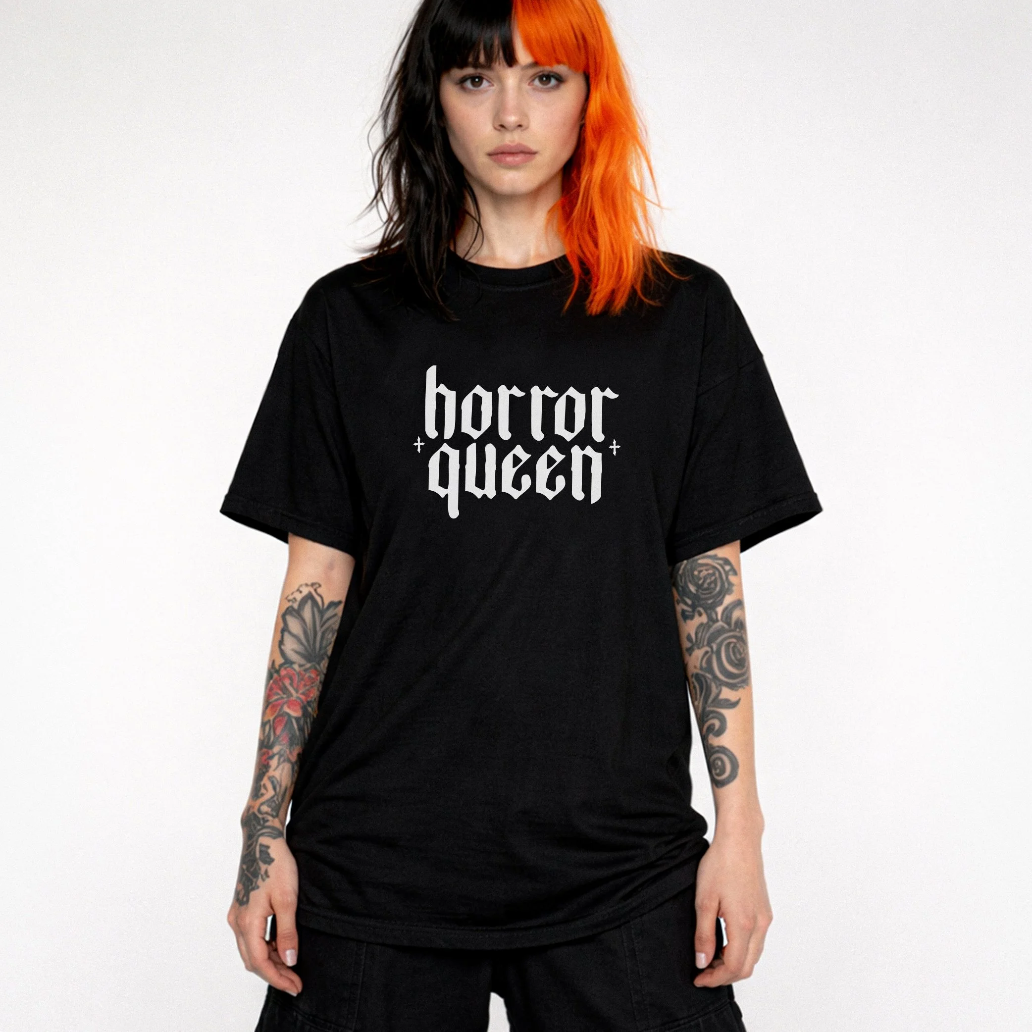A woman with black and orange hair wearing a black t-shirt that says 'horror queen' in gothic font.