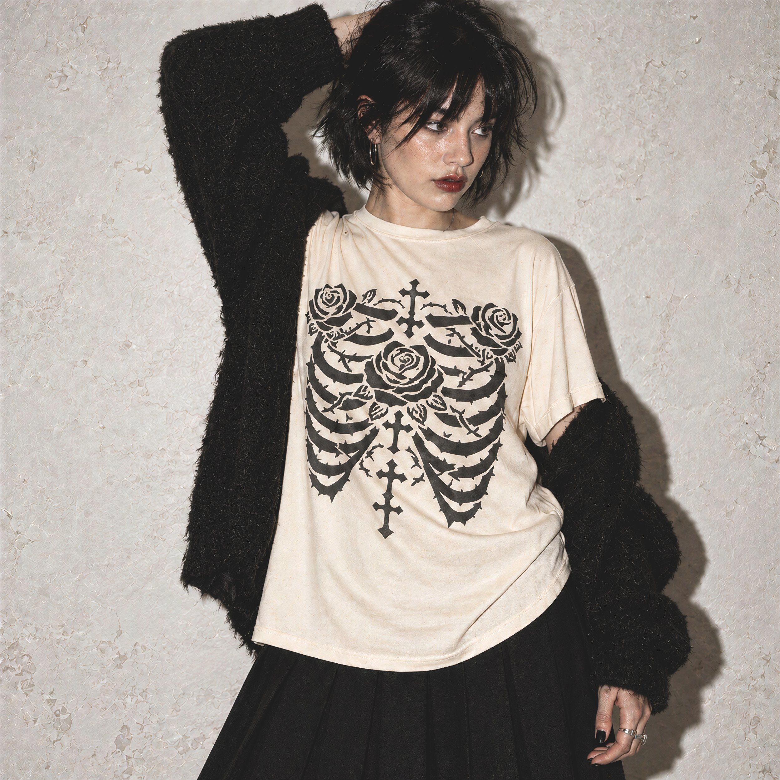 A woman with short dark hair wearing a black textured jacket and a cream shirt with a black floral skeleton design, standing against a textured wall. She is looking down with her right hand raised to her head.