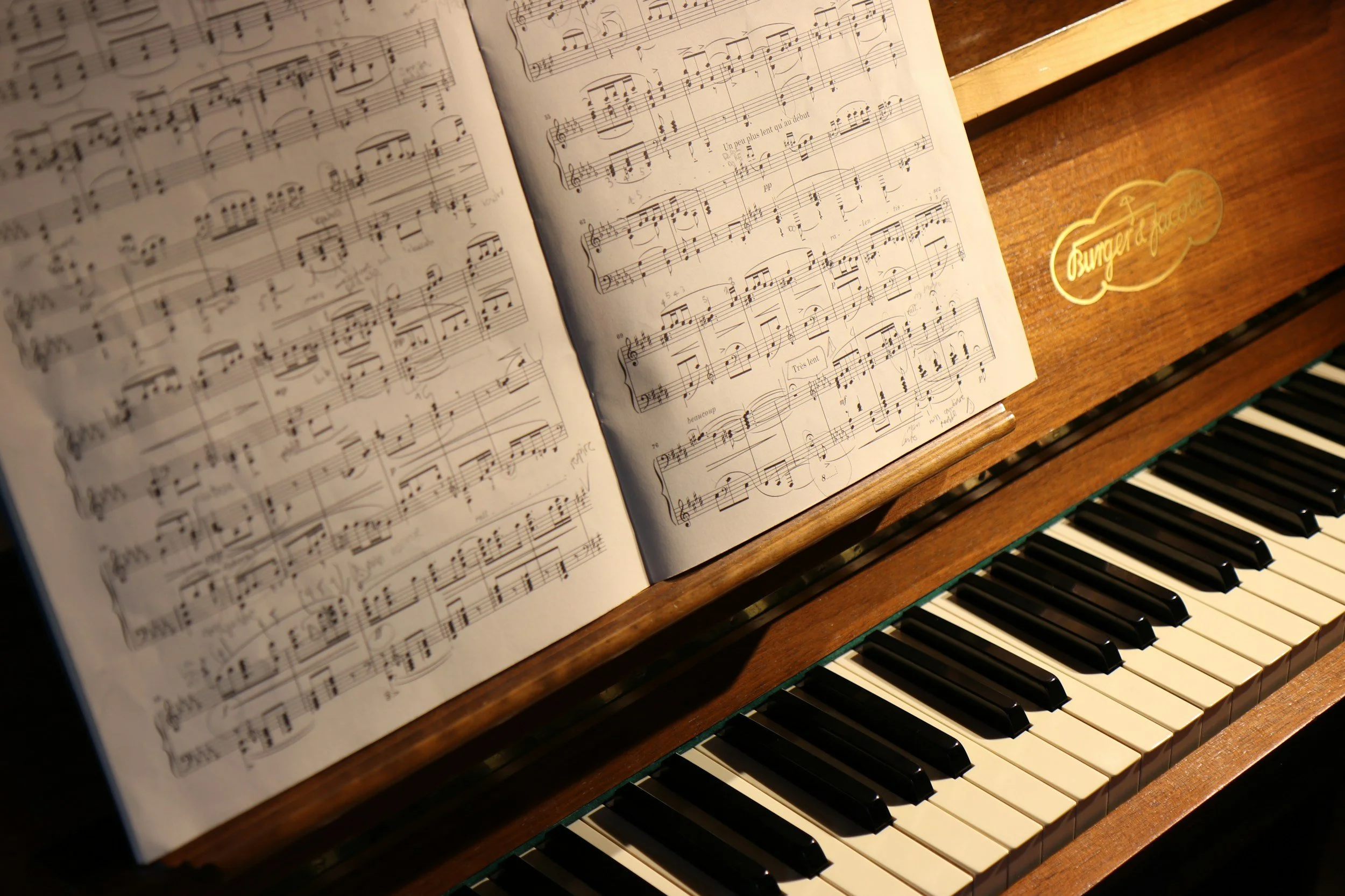 A wooden piano with sheet music open on the music stand, displaying musical notation.