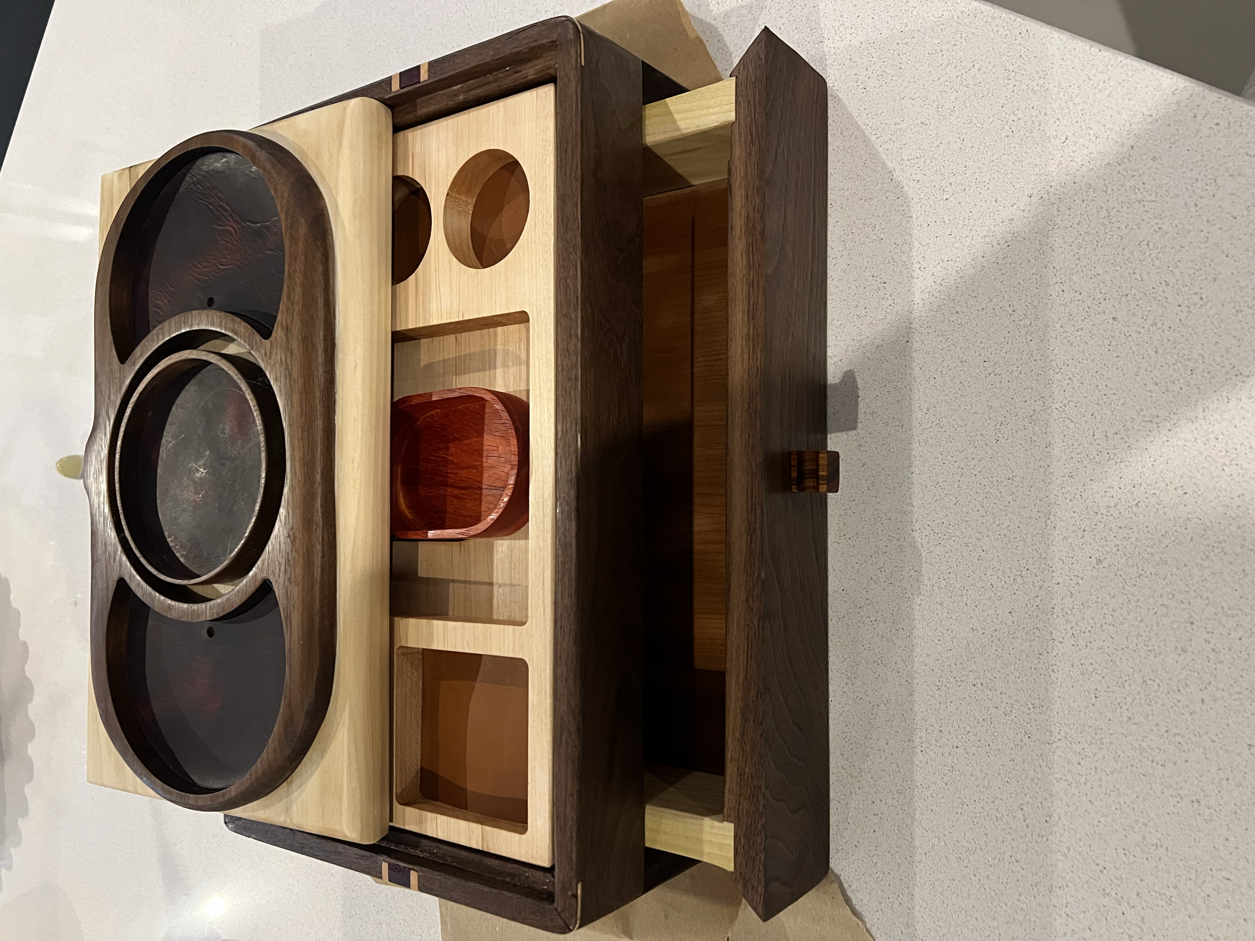 A wooden tea or coffee caddy with compartments for cups and a tea pot and inner circular holders for cups.