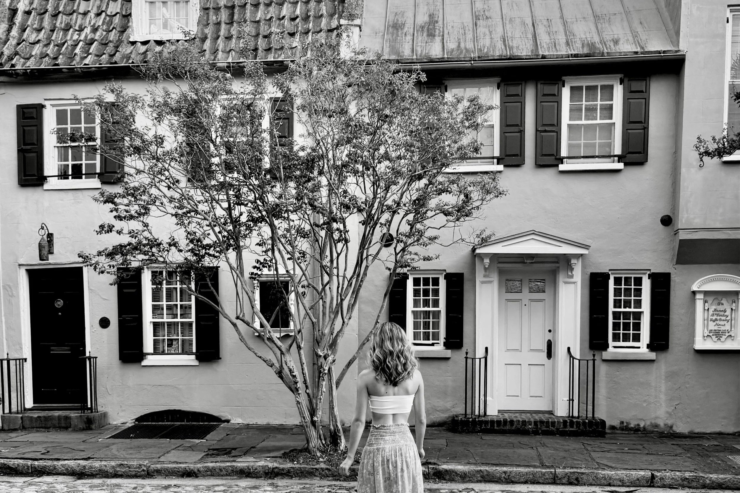 haley stands facing away from the camera, in a long skirt and tube top, looking at historic buildings in Charleston, South Carolina