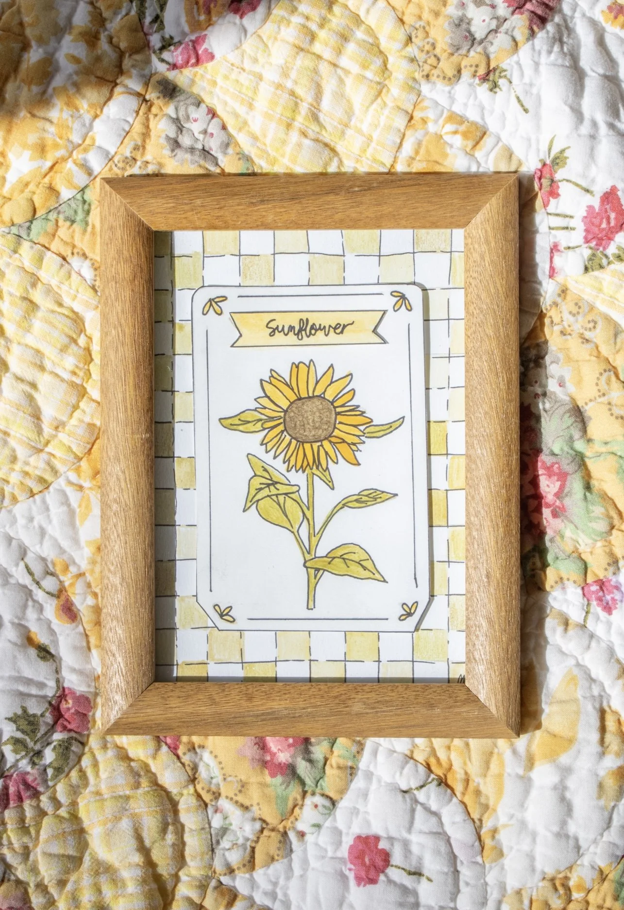 A seed packet inspired watercolor featuring a sunflower on a yellow checkered background