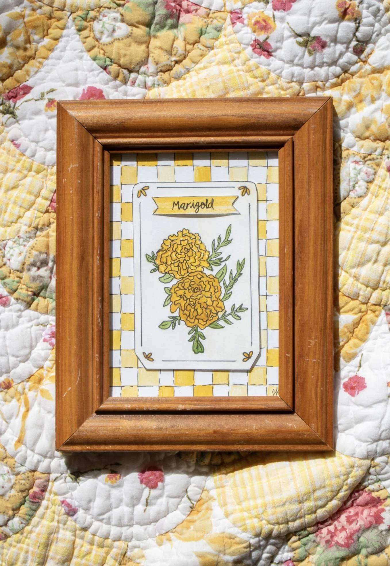A seed packet inspired watercolor featuring marigolds on a yellow checkered background 