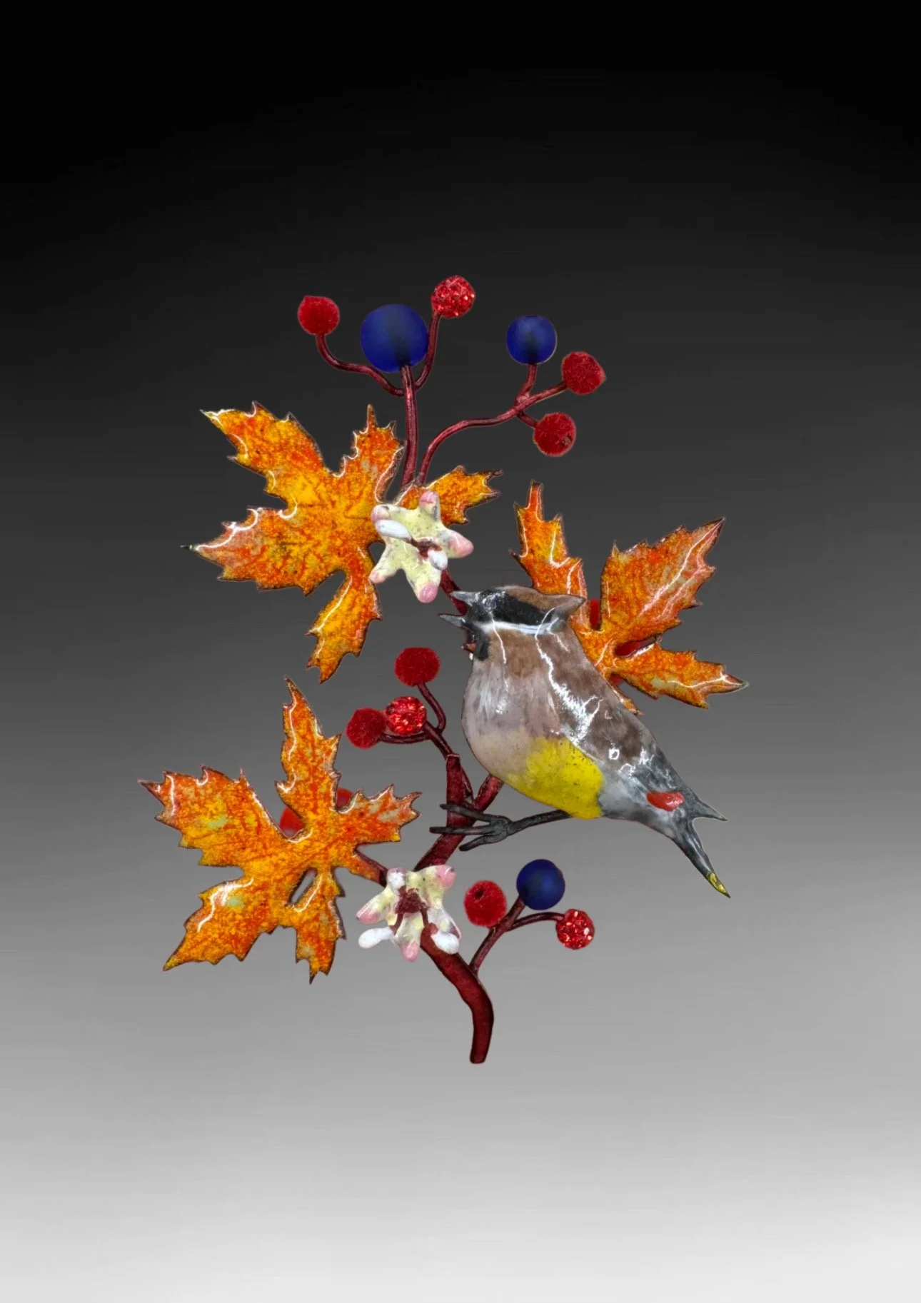 This pin features a painted enamel Cedar Waxwing perched on a segment of Virginia Creeper boasting its fall foliage. The leaves are enameled with oranges and yellows, while the copper stem is stained red with alcohol ink. Two lime green and pink flow