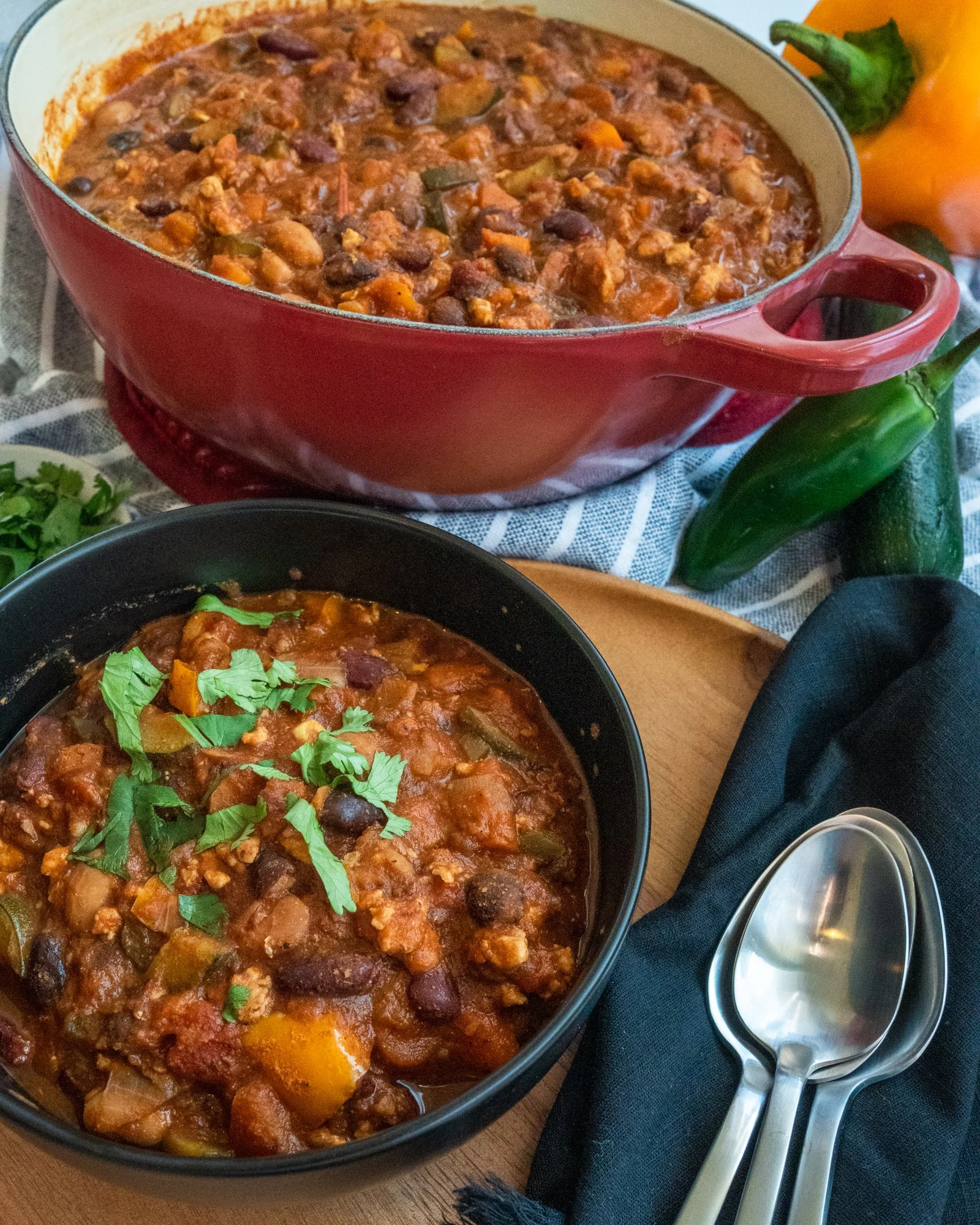 Chorizo chili made with Arizona Fresh pork or beef chorizo, simmered with beans and tomatoes, served in a bowl and a red Dutch oven, garnished with fresh cilantro.