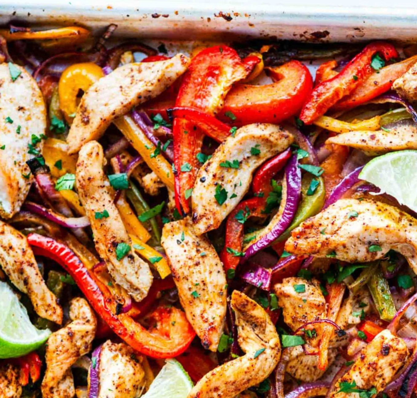 Sheet pan chicken fajitas made with Denmark Foods Thin Sliced Chicken Breast, colorful bell peppers, and red onions, served with warm tortillas, lime wedges, and fresh cilantro for an easy weeknight meal.