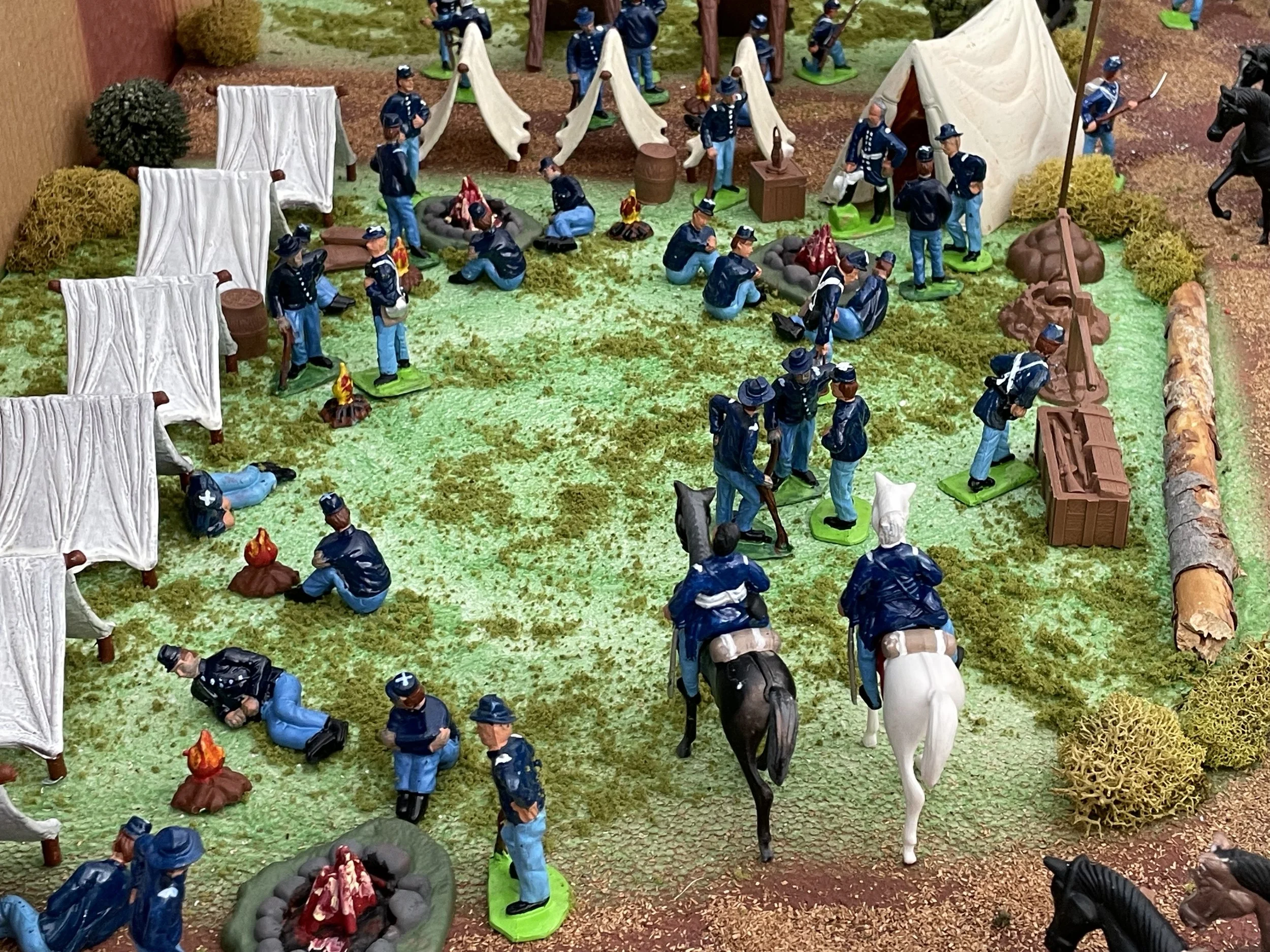 As officers ride slowly through the lines, camp life continues around them — men warming rations, cleaning muskets, or resting between duties. Mounted inspections were routine, a visible reminder of discipline and readiness. Even in quiet hours, the 