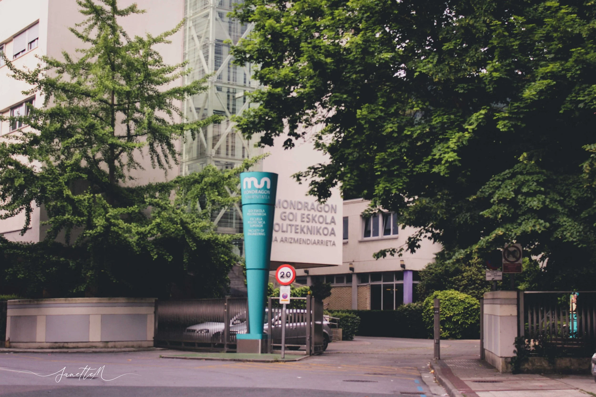 Entrada a la escuela superior de ingeniería en una calle rodeada de árboles y edificios.