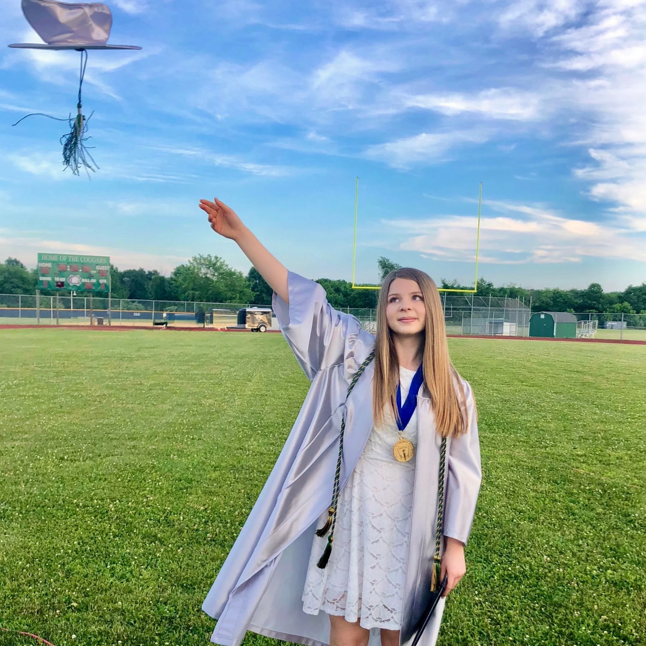 highschool girl at graduation throwing her cap