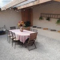 Table avec une nappe rose, couverte de fleurs, entourée de six chaises en extérieur sous un auvent.
