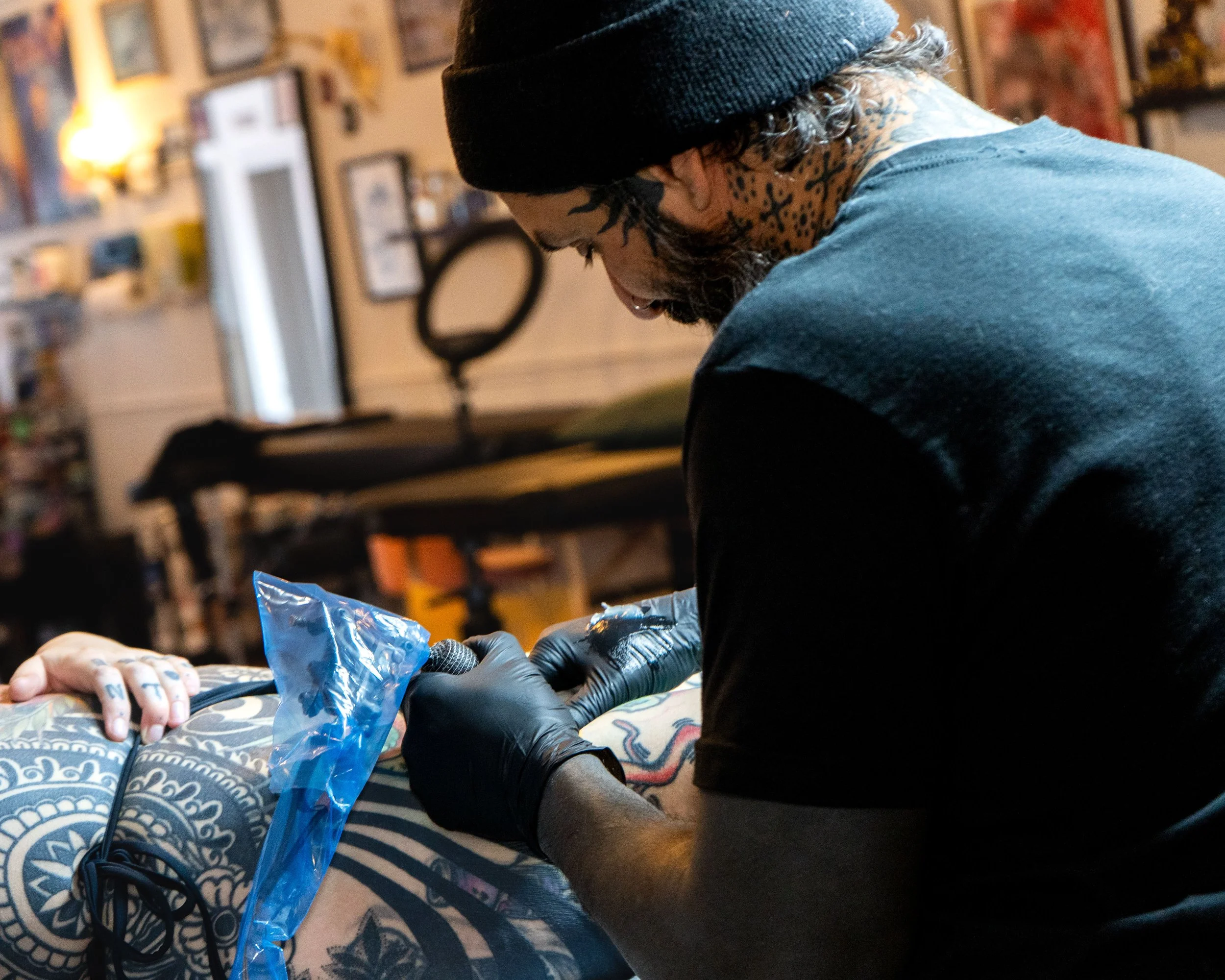 Tattoo artist creating a tattoo on a person's arm with tattoo equipment in a studio.