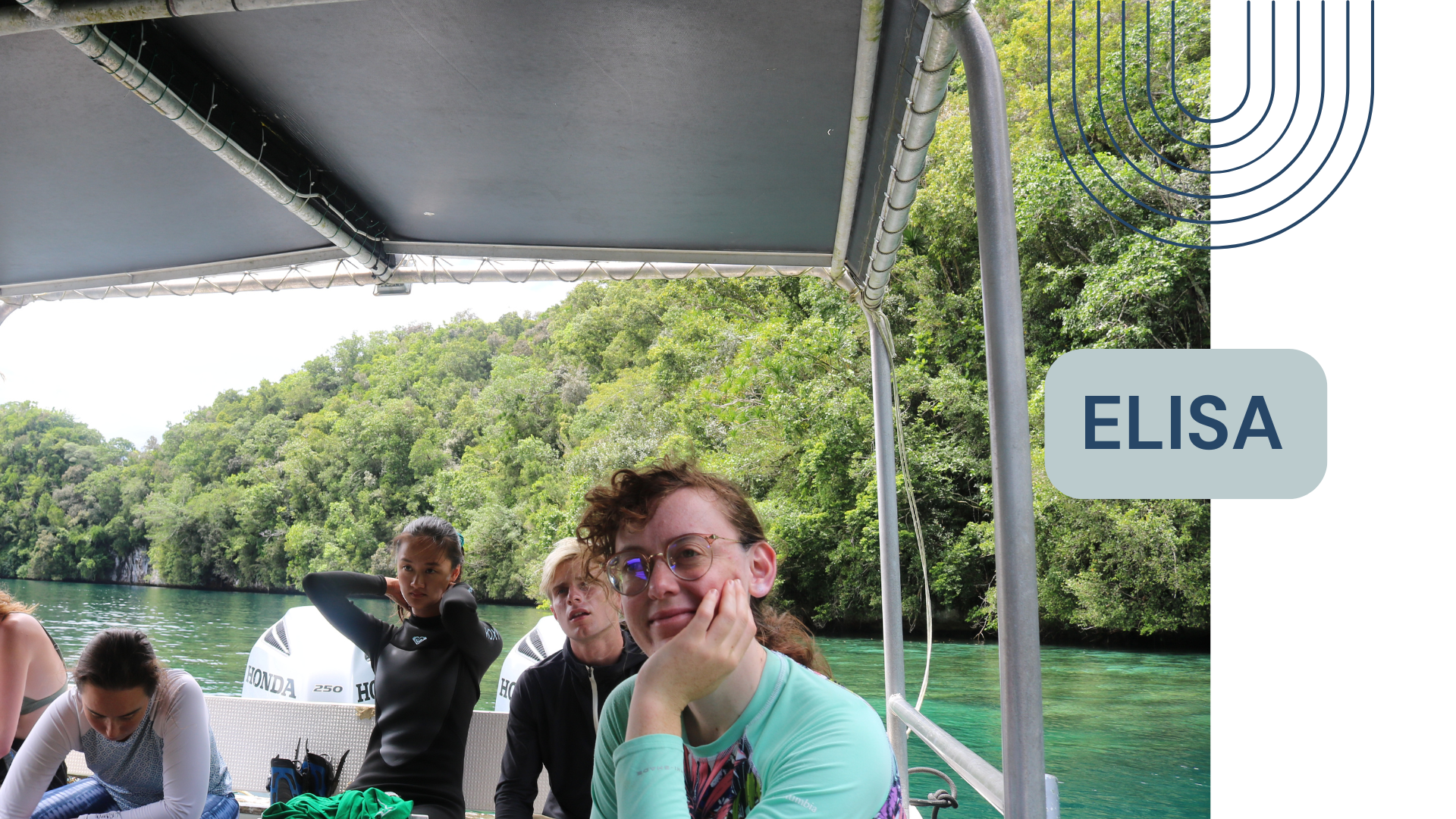 Group of four people sitting on a boat with twin Honda engines, surrounded by green trees and water, with one woman in the foreground smiling and resting her chin on her hand.