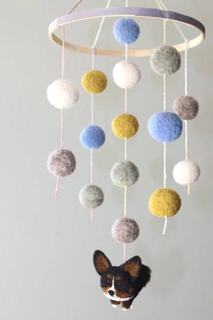 Felted wool mobile with colorful balls and a small plush dog hanging at the bottom.