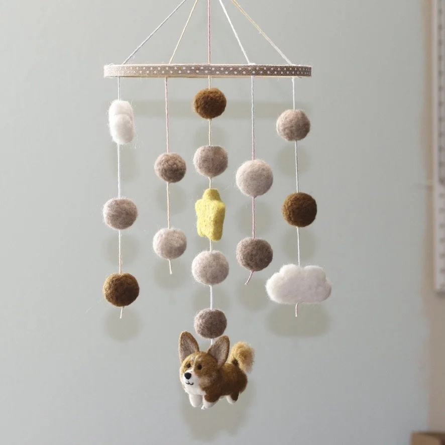 Felt mobile hanging with clouds, circles, a star, and a dog figure.