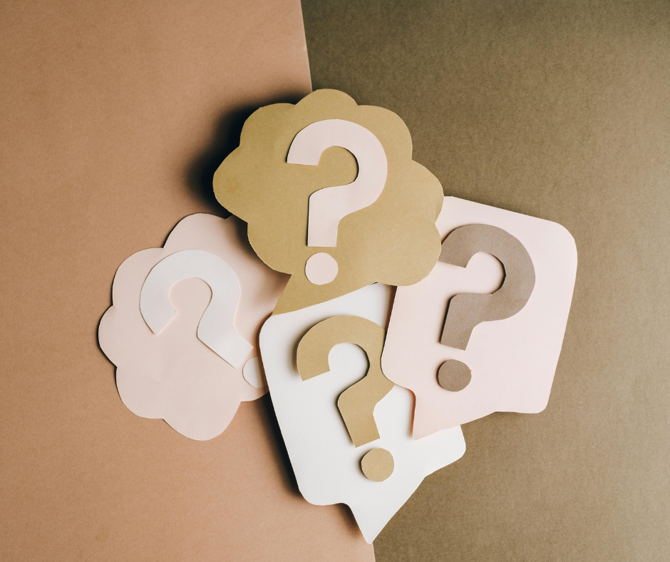 Multiple paper cutouts of question marks in white, beige, and brown, placed on a dual-colored background of pink and brown.