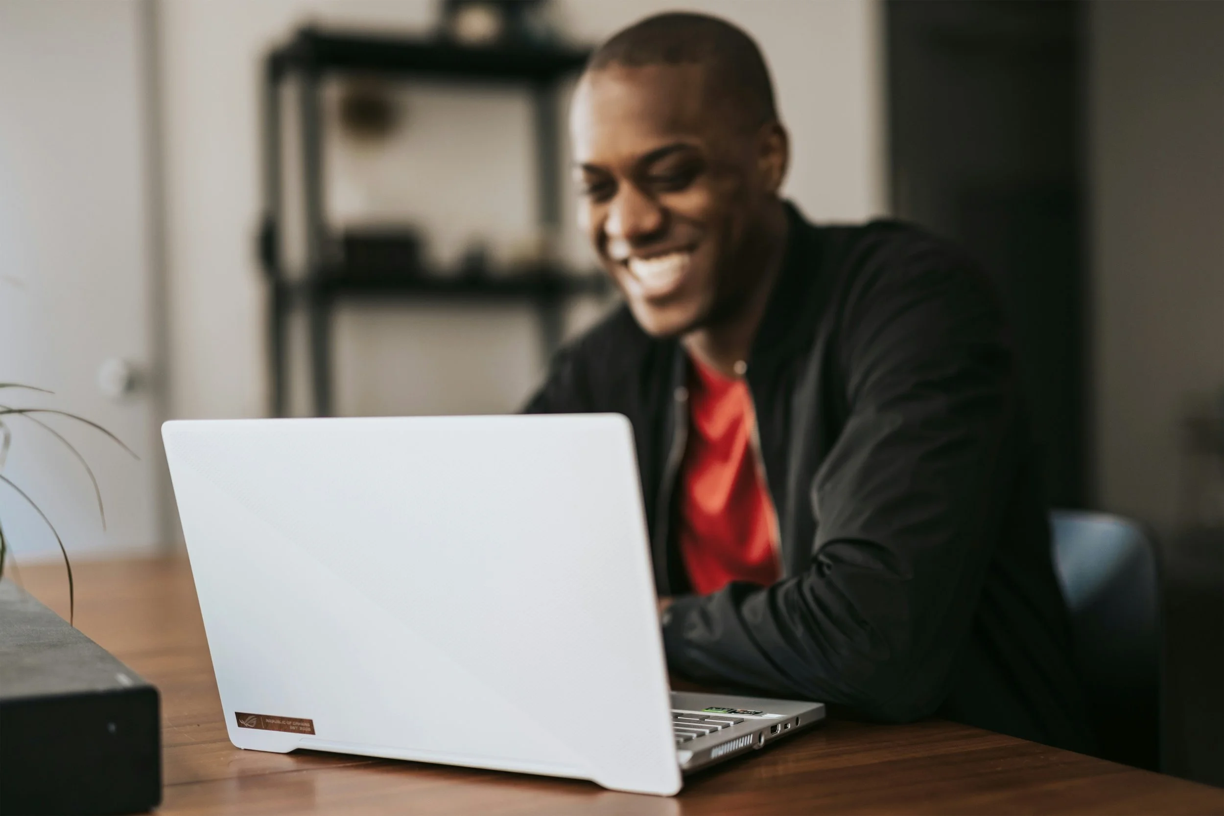 Man happily looking at his laptop from his dining room table