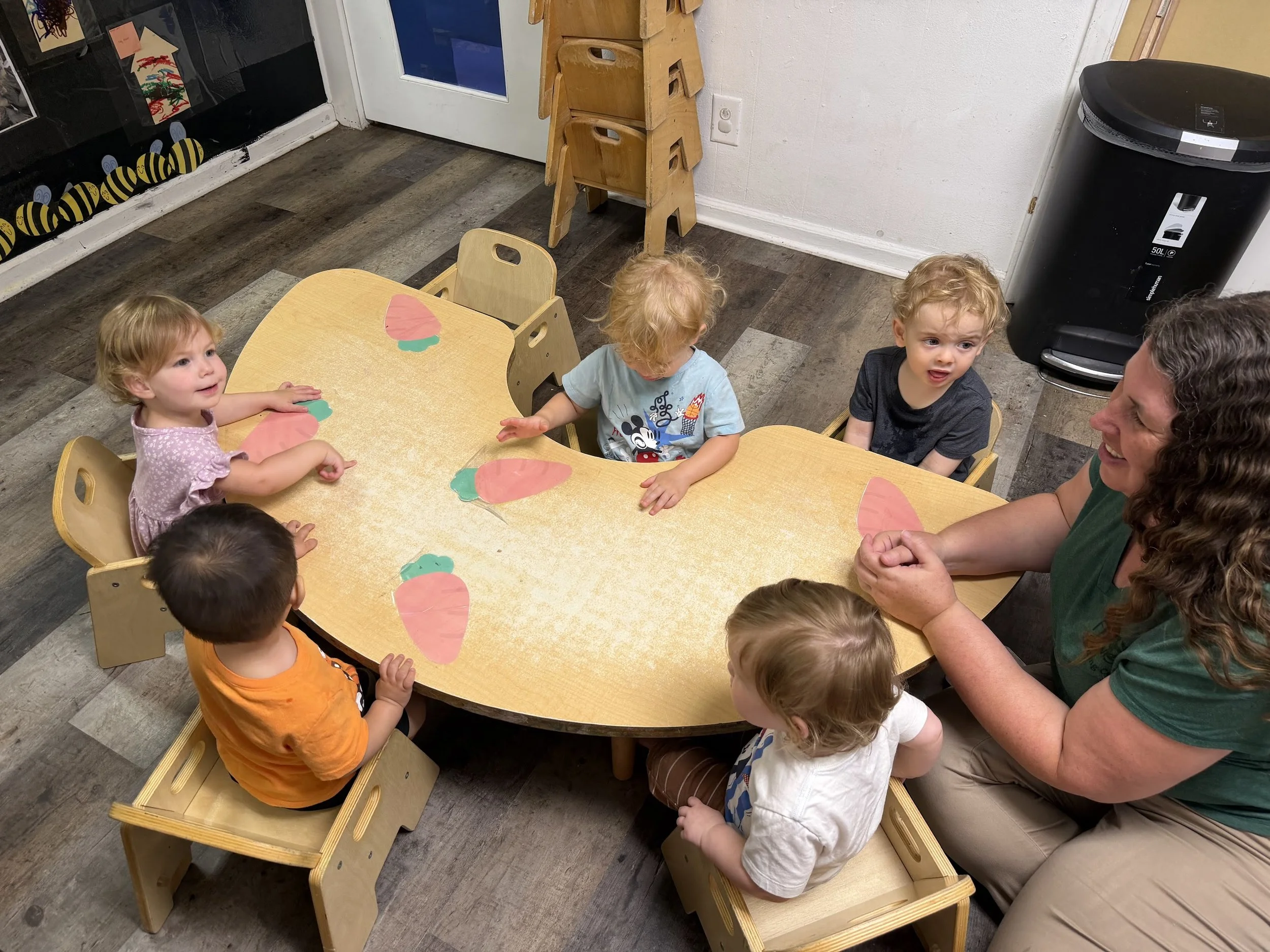 Toddlers sitting.at a table with a teacher doing an activity