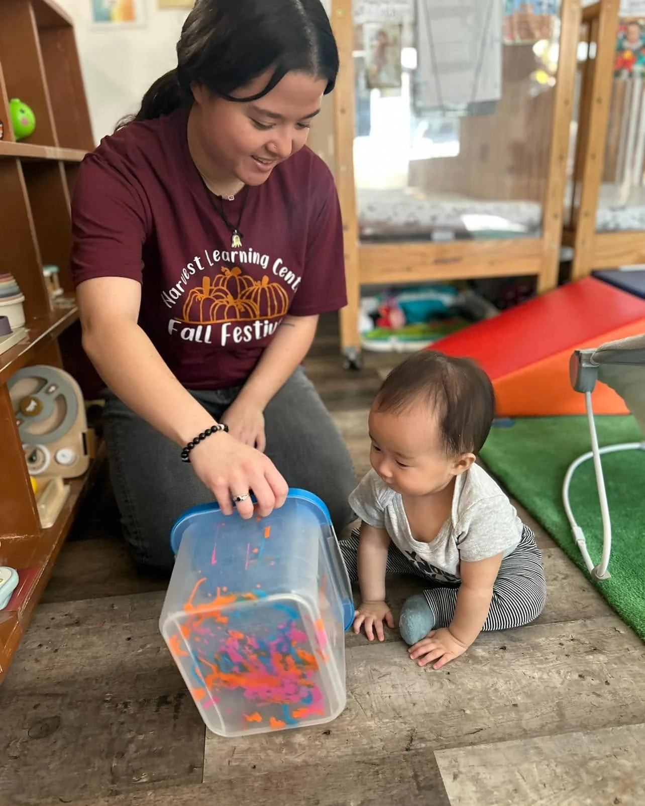 An infant and teacher playing with paint