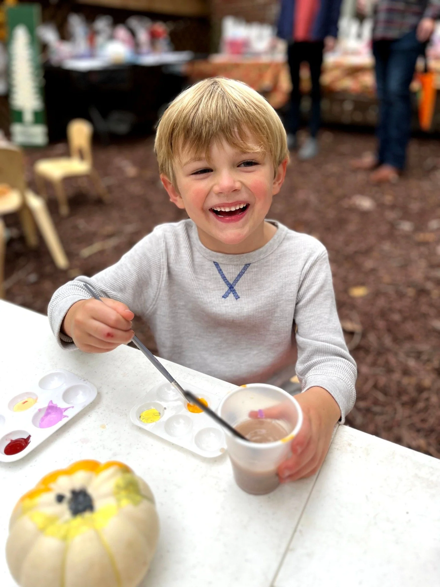 A preschooler smiling while painting a pumkin