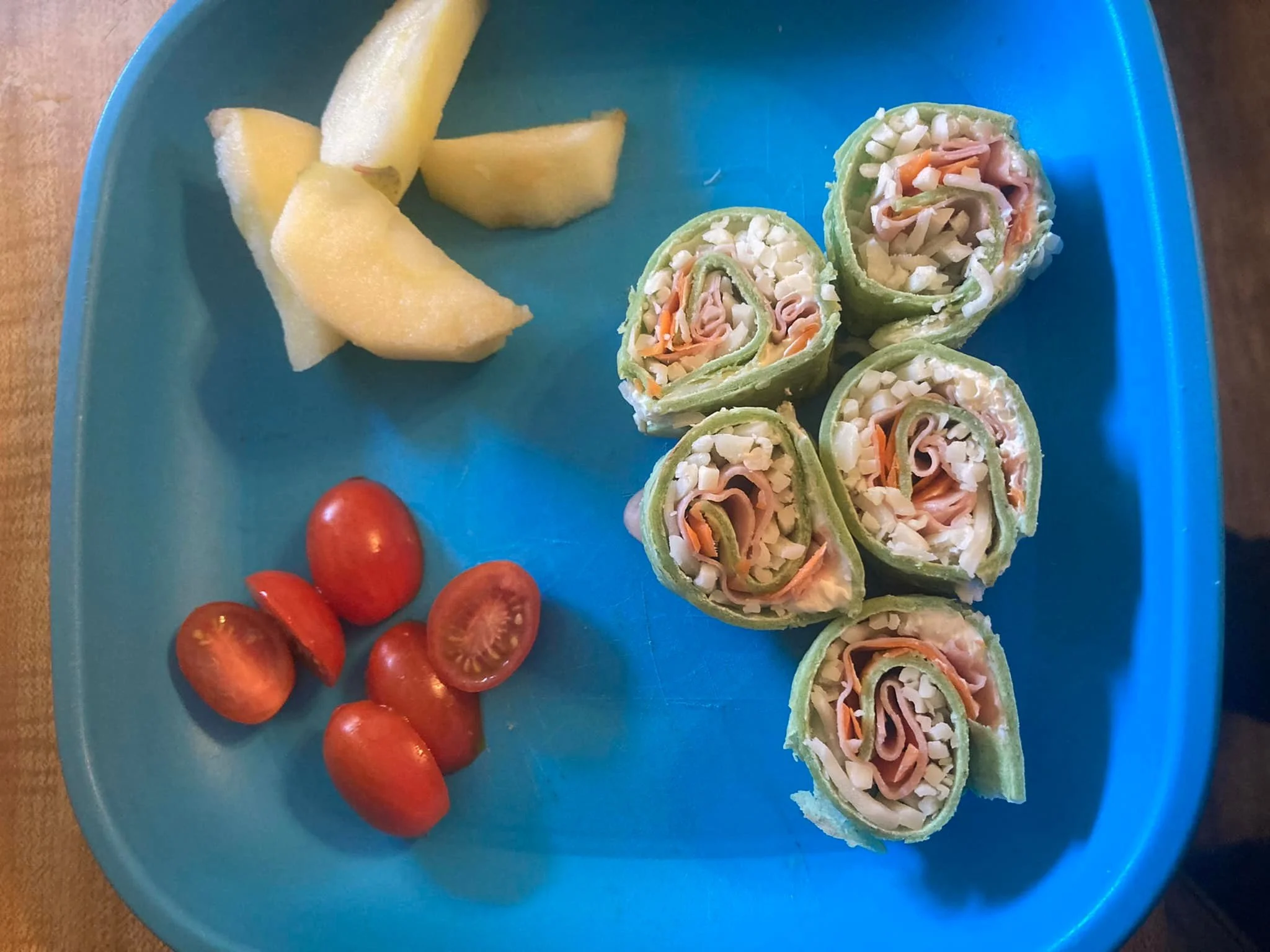Spinach flour tortillas with meat and cheese, as well as fresh tomatoes and apples