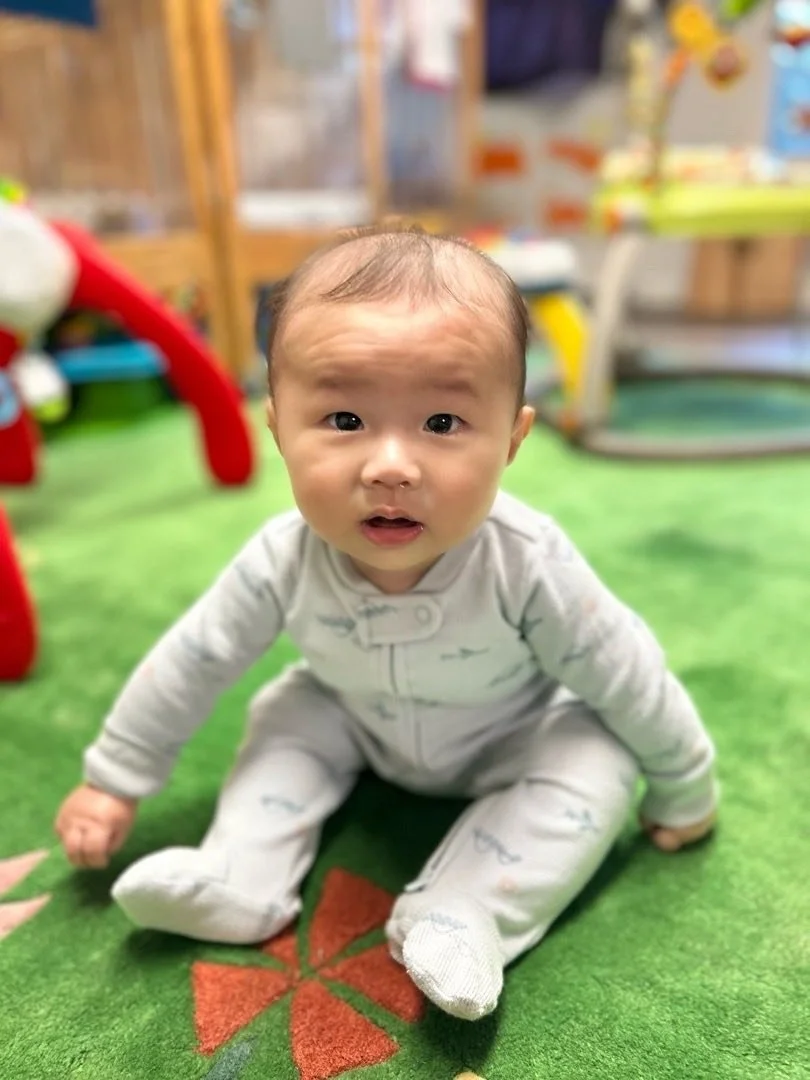 An infant sitting up on a mat