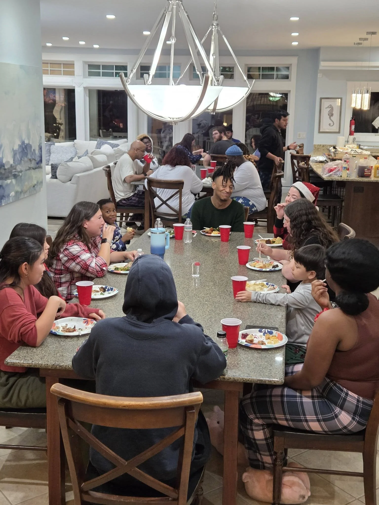 HLC staff and family gathered around a dining table having a holiday meal, with some wearing Christmas accessories.