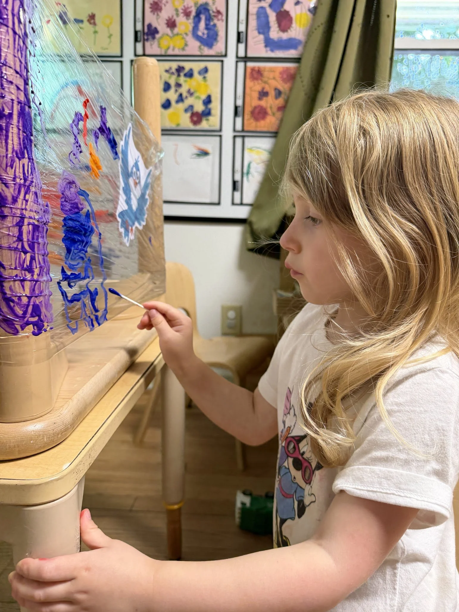 A pre-k girl doing an art project with paint
