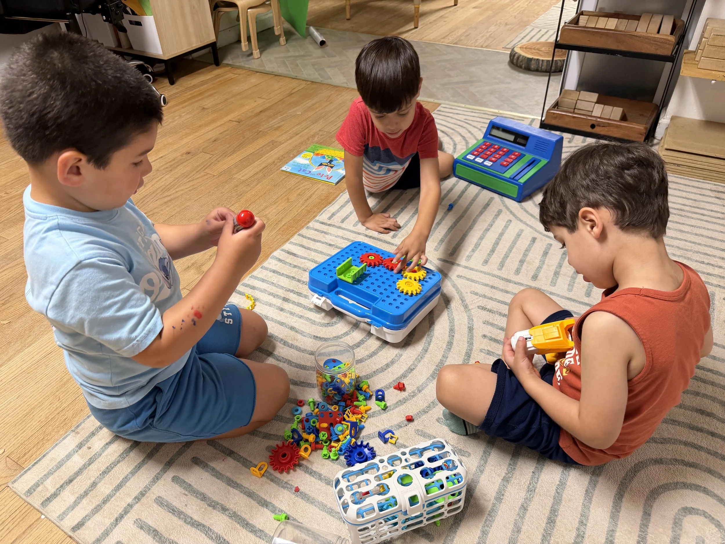 Three pre-k children playing with toys on the floor