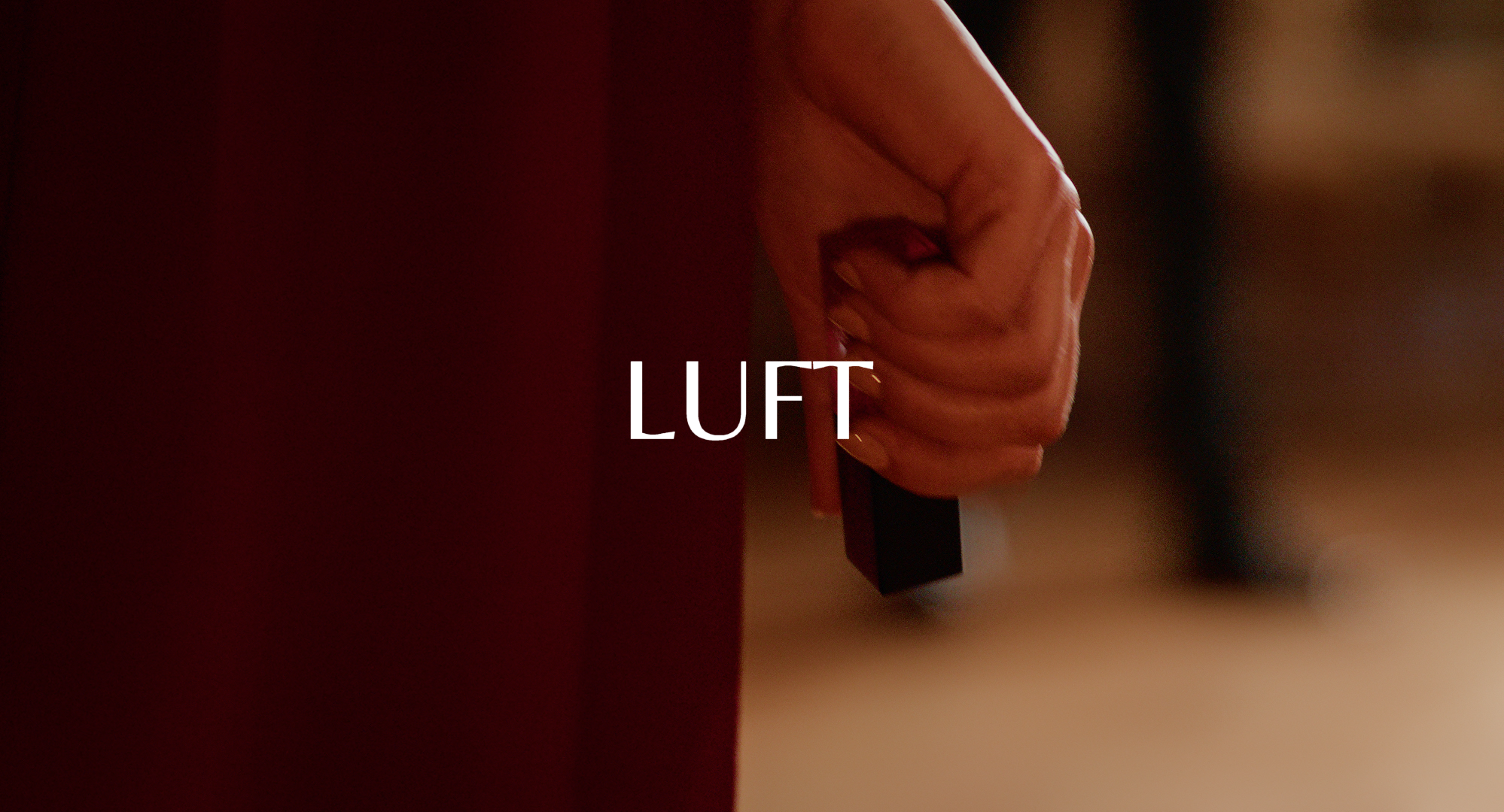 A close-up of a hand holding a black rectangular object with the word 'LUFT' overlaid in the center.