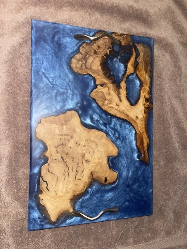 A wood and resin art piece resembling a map of two landmasses surrounded by water.