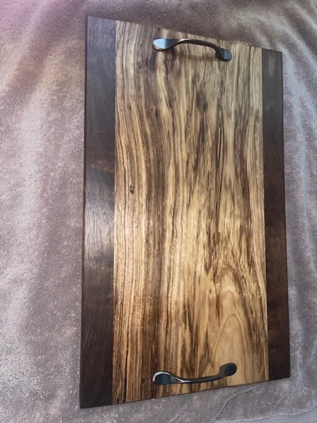 Wooden box with black metal handles on a textured gray surface.