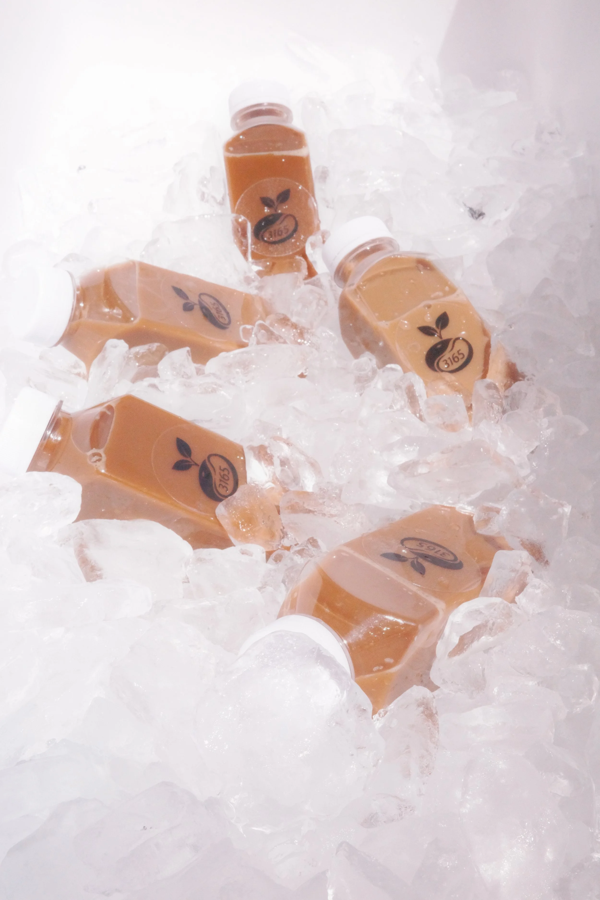 Three bottled juice drinks displayed on ice inside the 3165 Coffee mobile beverage cooler during a luxury catered event setup in Sacramento, California.
