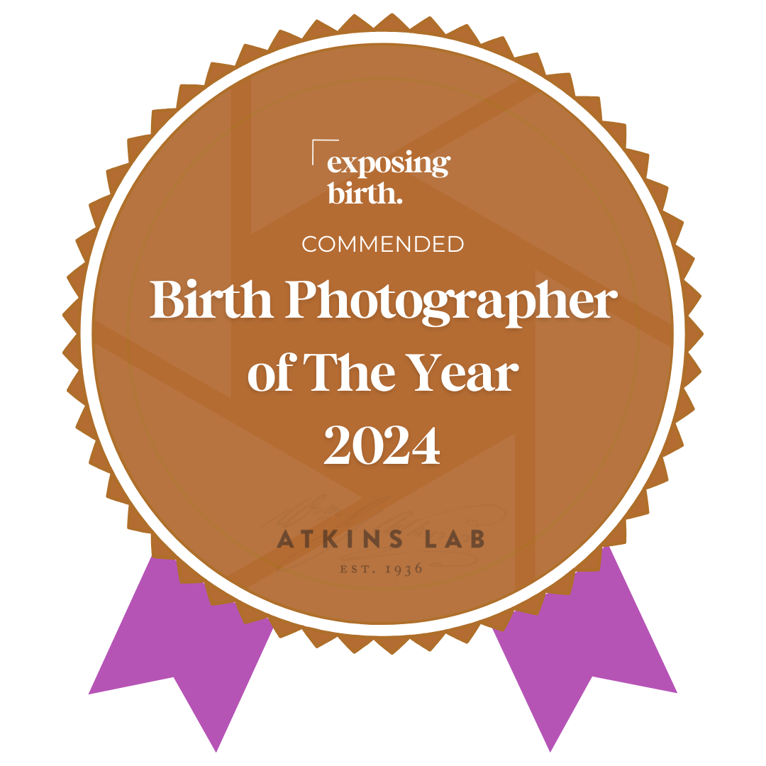 Award badge with brown background and white border, recognizing the 'Birth Photographer of the Year 2024' by Atkins Lab, highlighting exposure of birth.