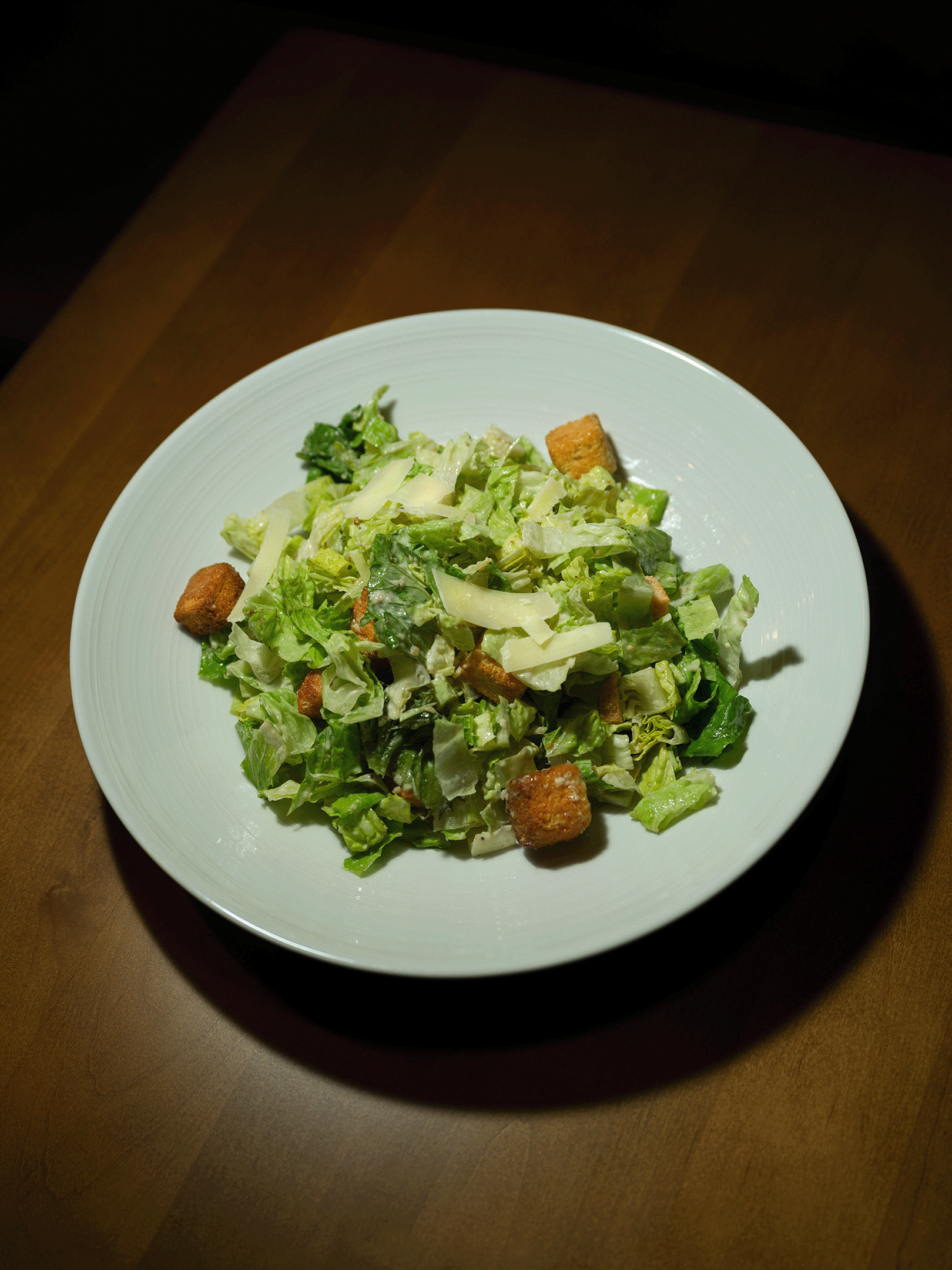 A classic Caesar salad served at Roosevelts Restaurant & Bar at Live Oaks Golf Club in Brandon, Mississippi. Crisp chopped romaine tossed in Caesar dressing, topped with shaved parmesan and golden croutons.