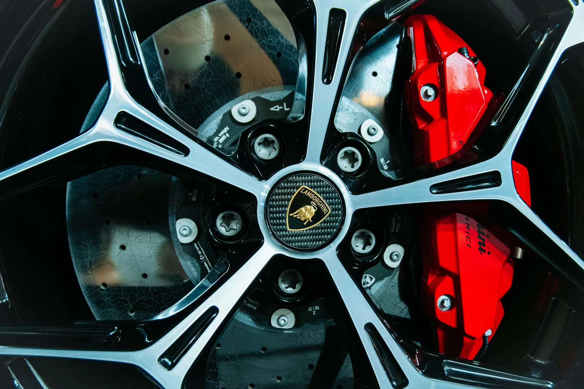 Close-up of a Lamborghini wheel with red brakes and the Lamborghini emblem in the center.