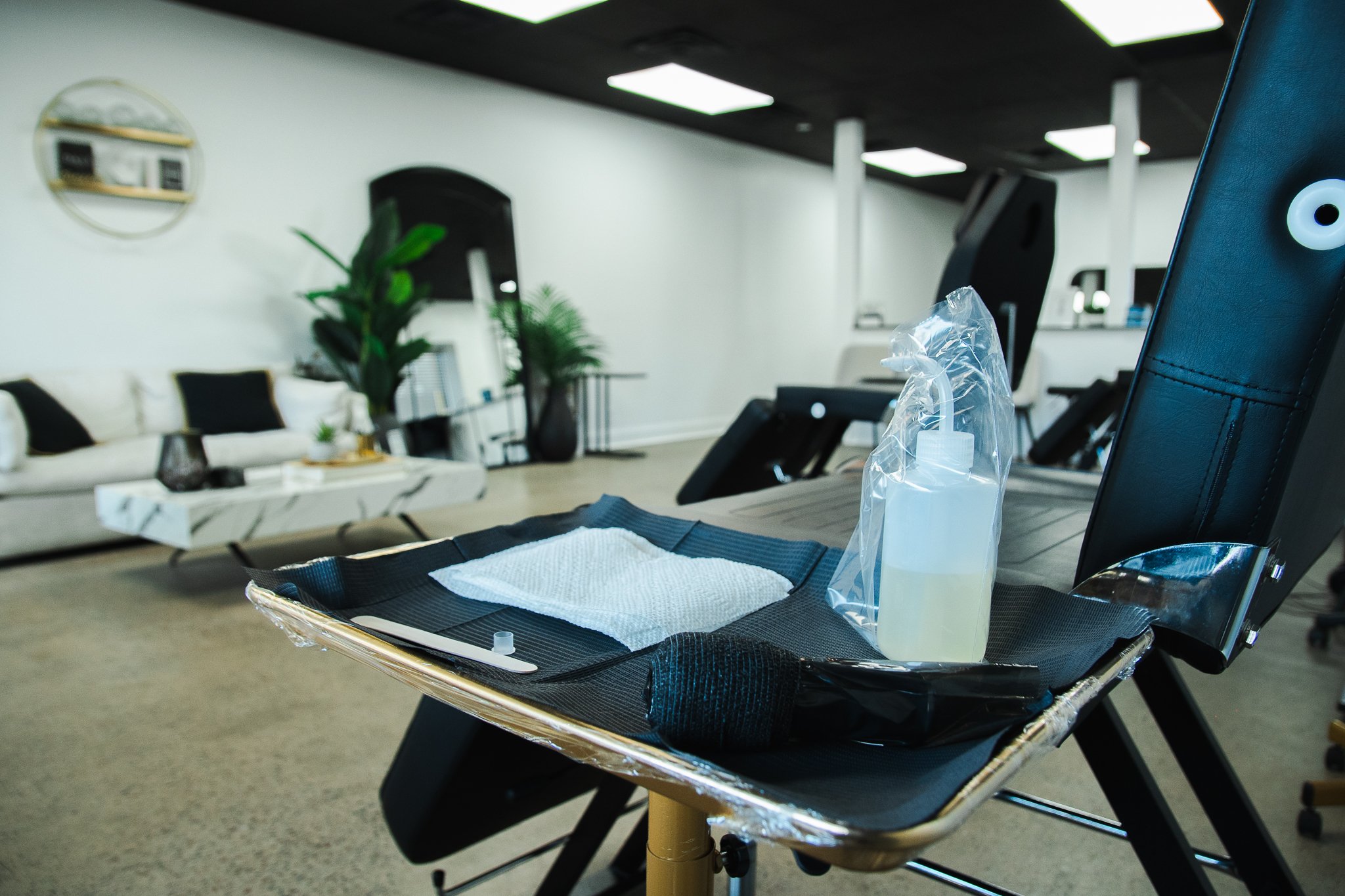 Sanitizing station with hand sanitizer, wipe, and disposable gloves on a chair in a modern lounge or office space