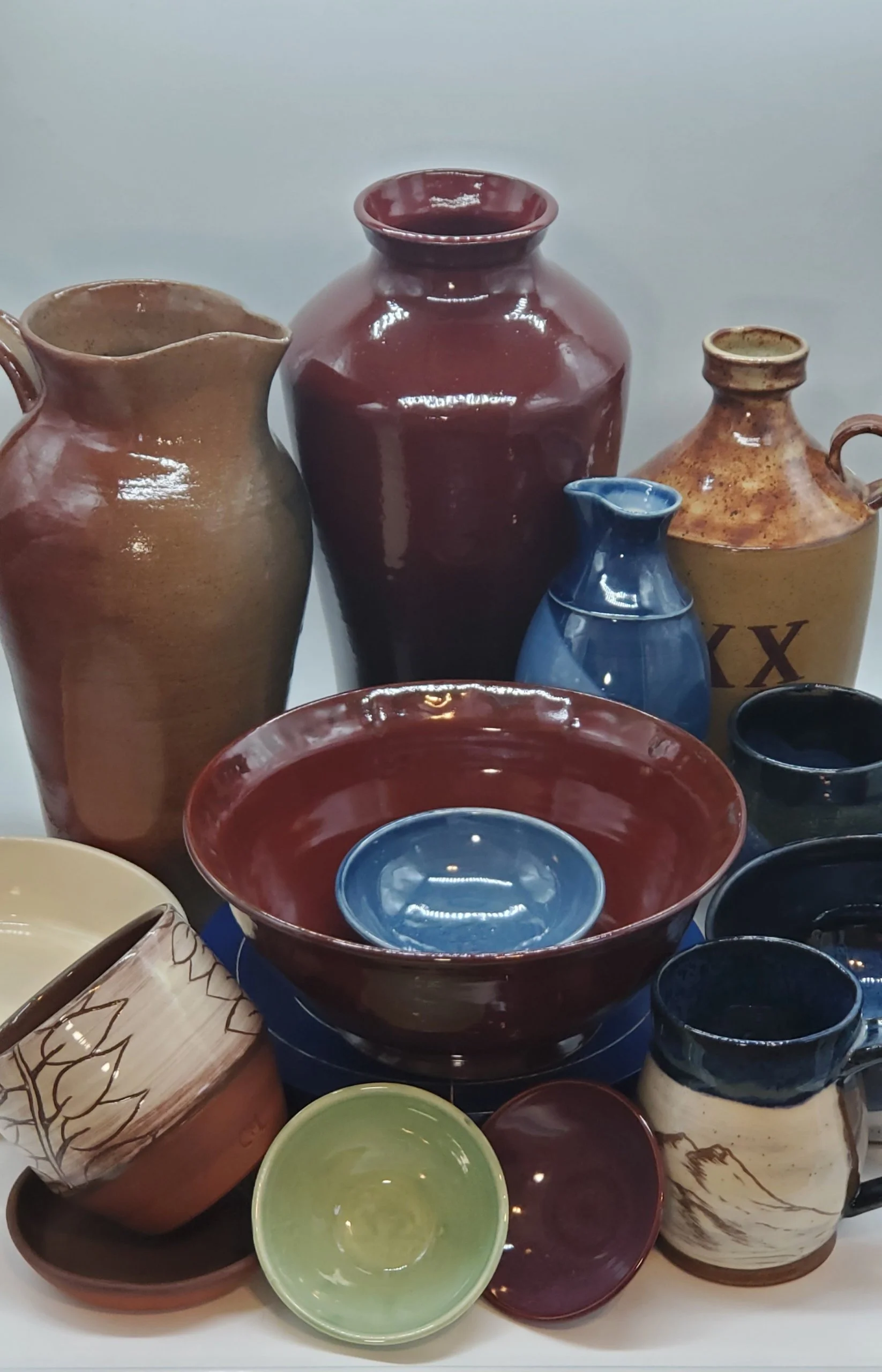 An assortment of colorful ceramic pottery, including vases, bowls, and mugs, displayed together.
