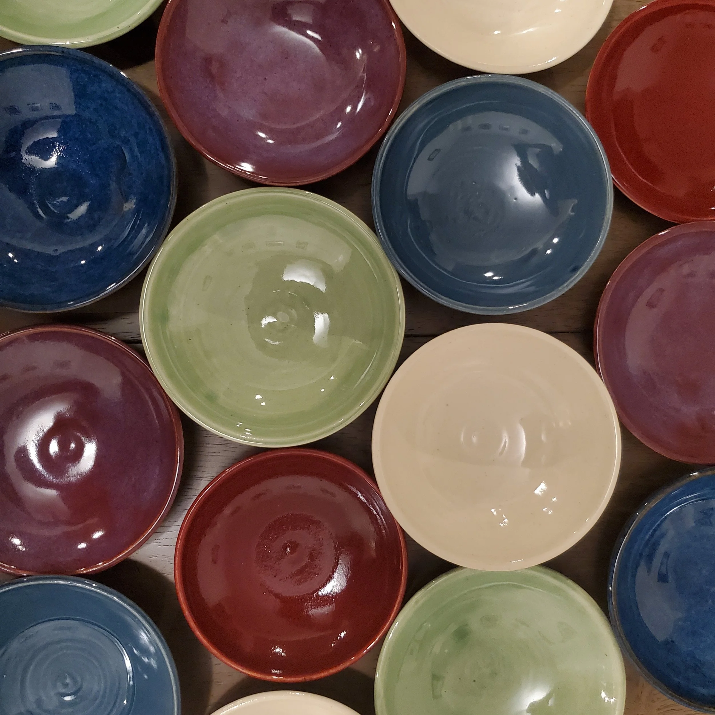 Colorful ceramic bowls arranged upside down on a wooden surface.
