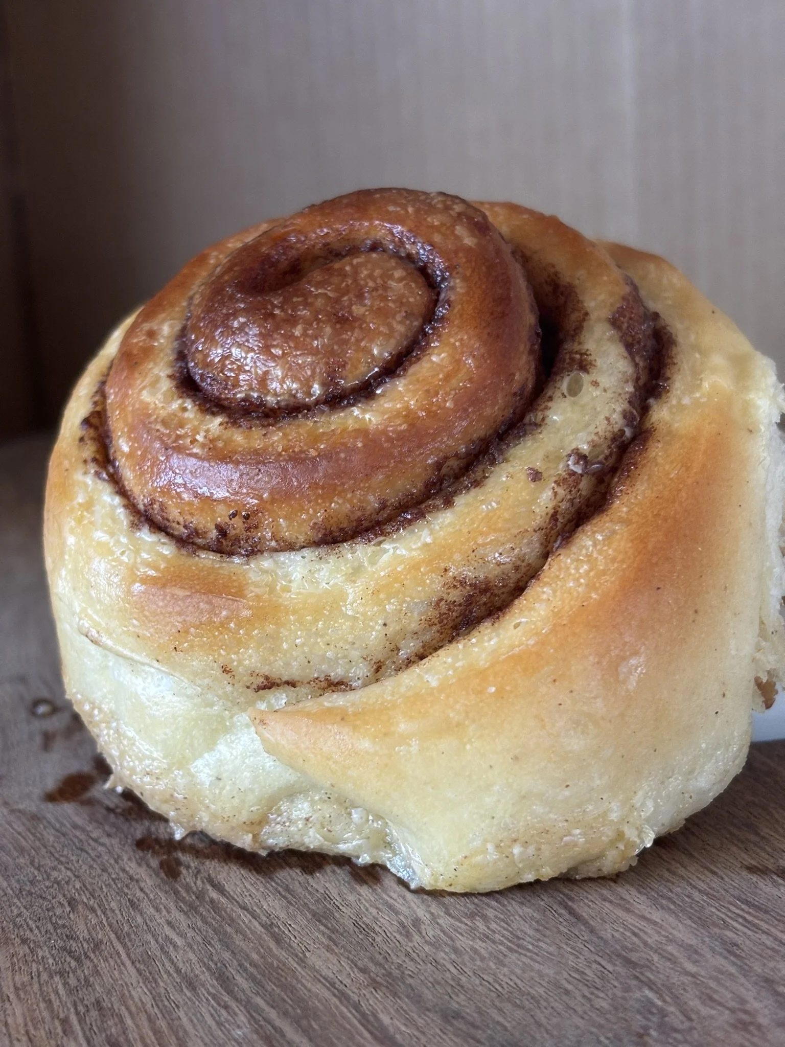 Close up of an organic cinnamon roll on a wooden cutting board.