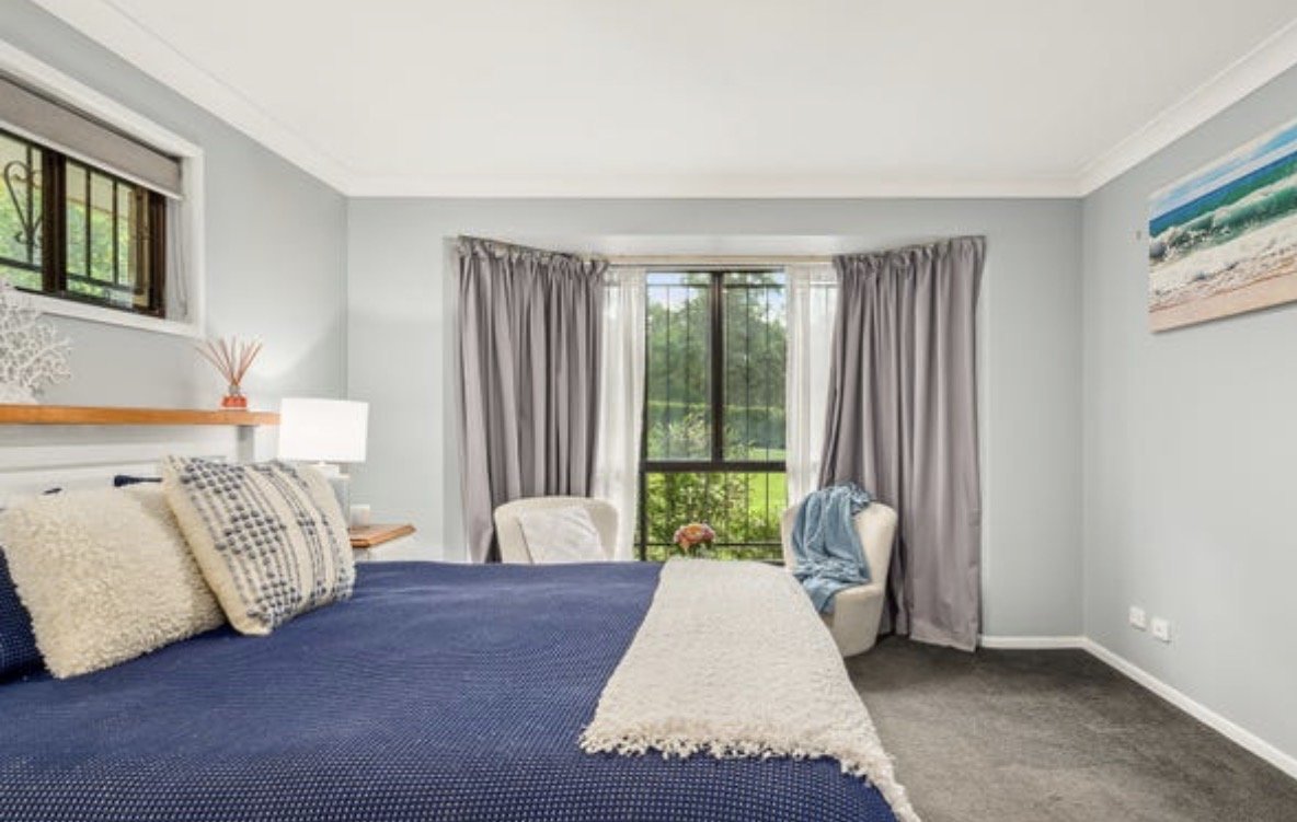 Light-filled bedroom with large window, grey curtains and neutral styling