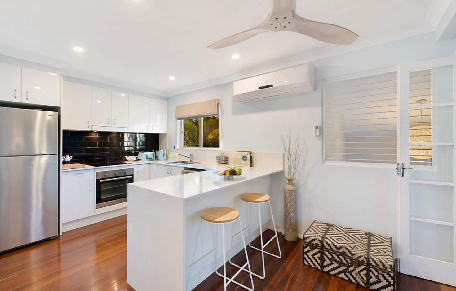 Modern kitchen breakfast bar with fan, design elements such as a suitcase, vase, and kitchen appliances