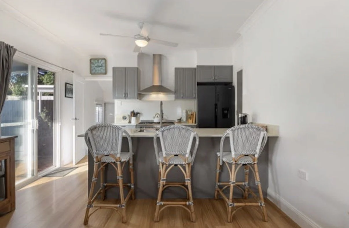 Renovated kitchen with breakfast bar seating, grey cabinetry and modern appliances