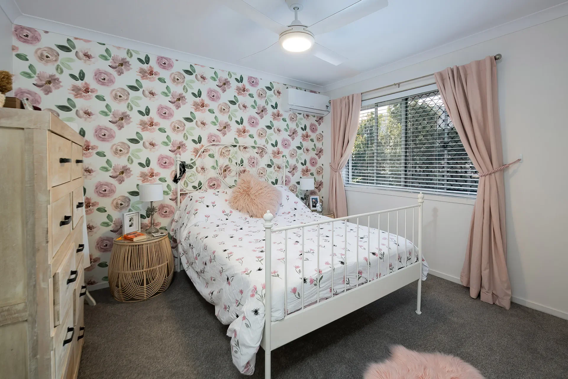 Styled children’s bedroom with floral feature wall, soft tones and decorative accents