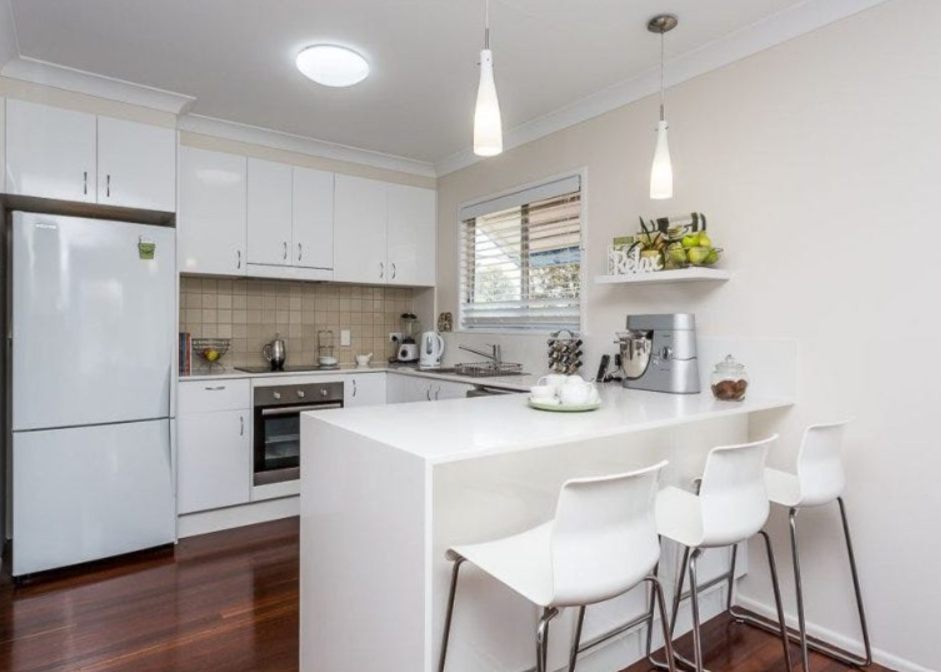 Older kitchen with white cabinetry, timber floors and basic island bench