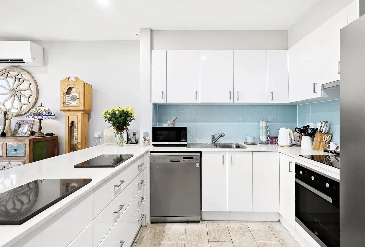 Contemporary white kitchen with stone benchtops, glass splashback and modern appliances