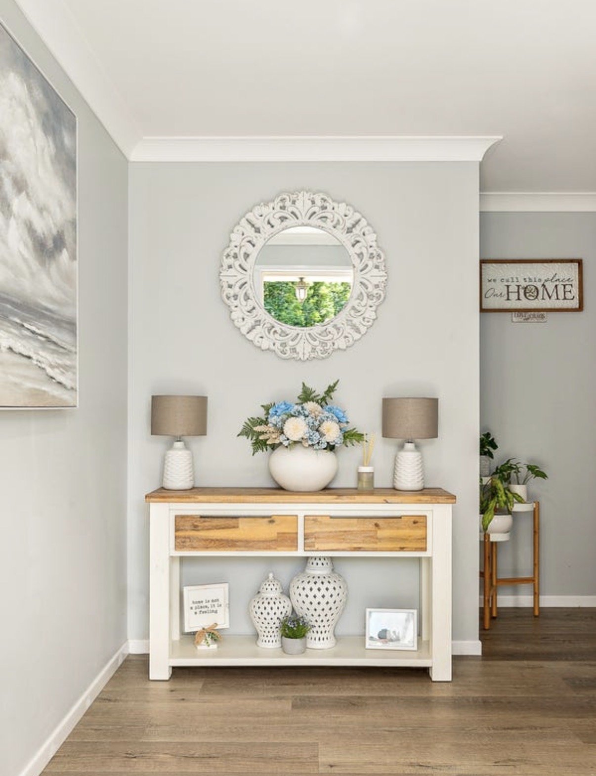 Styled entry console with decorative mirror, table lamps and floral arrangement